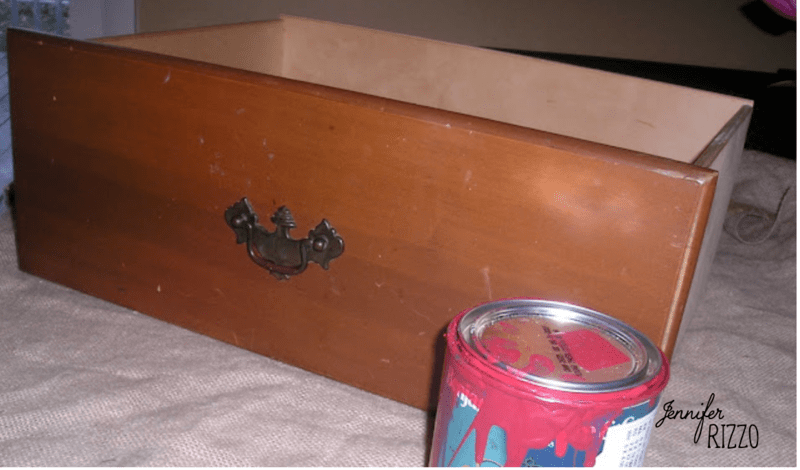 A wooden drawer, repurposed from a dresser into a planter, sits on a surface next to an open can of red paint. The name "Jennifer Rizzo" appears in the corner.