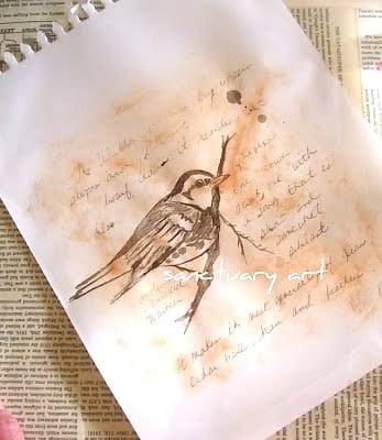 A sketch of a bird on a branch with handwritten notes, rendered in charming Sepia Bird Art style, rests on a white sheet of paper atop printed book pages.