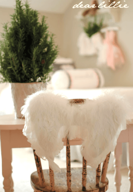 A small potted evergreen sits on a desk, while a wooden chair with white feathered angel wings draped over the back is in the foreground, capturing the charm of Traditional Holiday Decor from Holiday Housewalk 2011 Day 2.