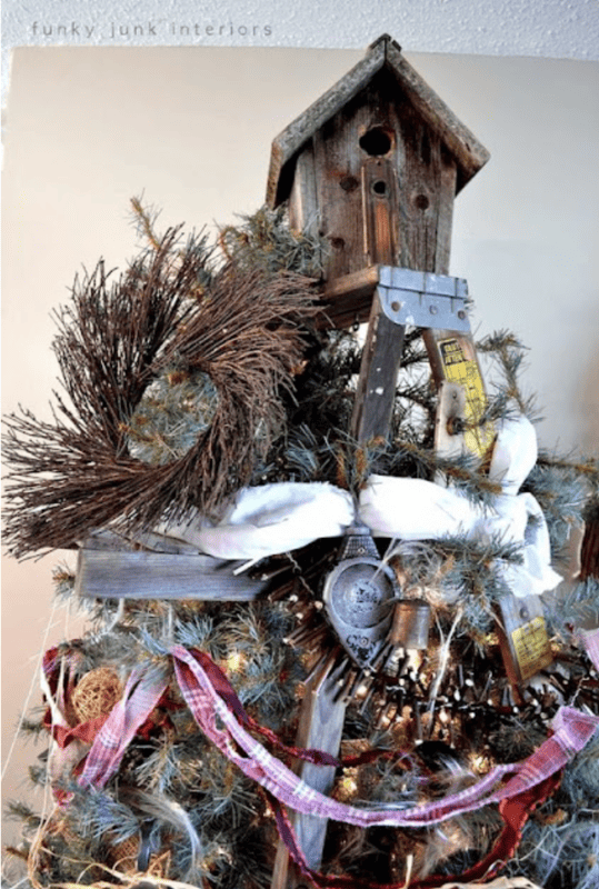 A rustic Christmas tree, part of the Welcome to the Virtual Holiday Housewalk 2011, is decorated with a birdhouse, an old wooden ladder, pine branches, tools, and ribbon for a charming vintage farmhouse look.