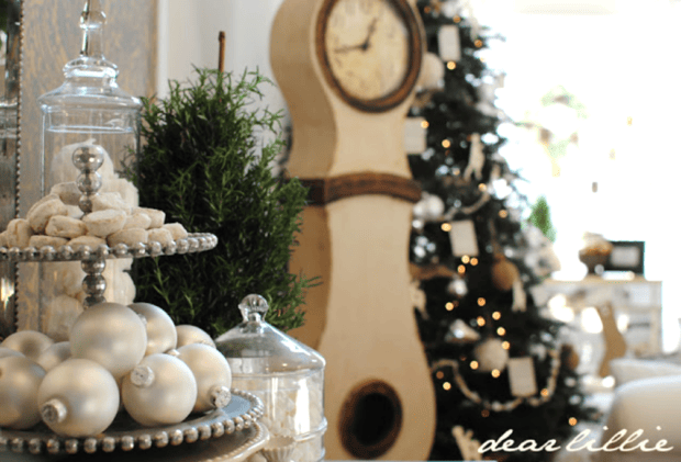 Silver ornaments and cookies on a tiered tray sit near a Christmas tree with lights and a tall vintage clock, creating a bright, festive room perfect for Holiday Housewalk 2011 Day 2 and showcasing traditional holiday decor.