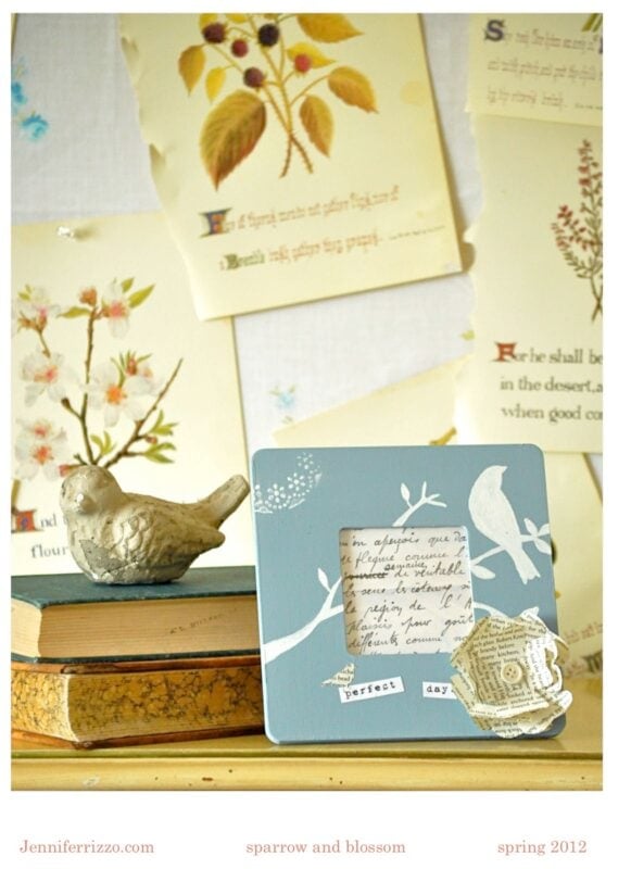 A ceramic bird figurine and a decorative photo frame sit on stacked books, with botanical prints and sheet music pages pinned on the wall behind them.