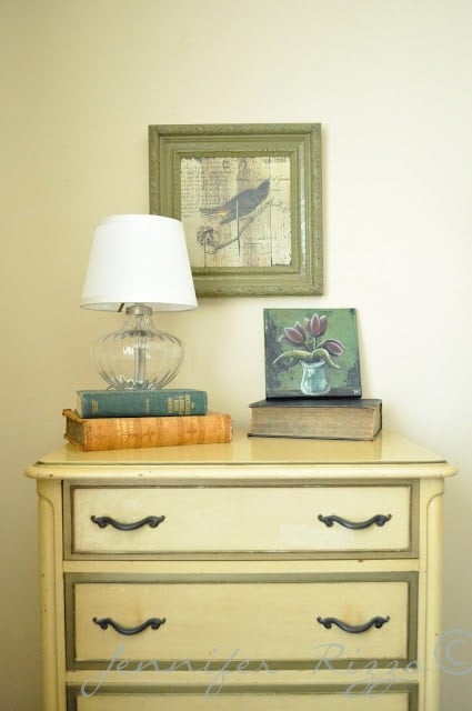 yellow dresser with a clear lamp and bird art