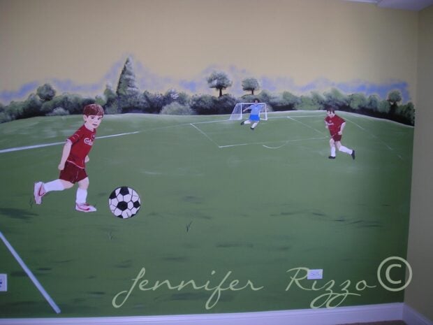 A painted wall mural depicts two children in red soccer uniforms playing on a grassy field, with a goal and trees in the background.