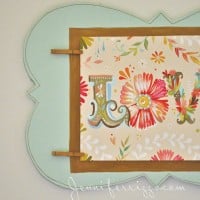 Decorative floral artwork featuring an ornate "L" on a colorful background, elegantly showcased on an art display board with a stylish teal and brown frame. Make A Pretty Art Display Board 