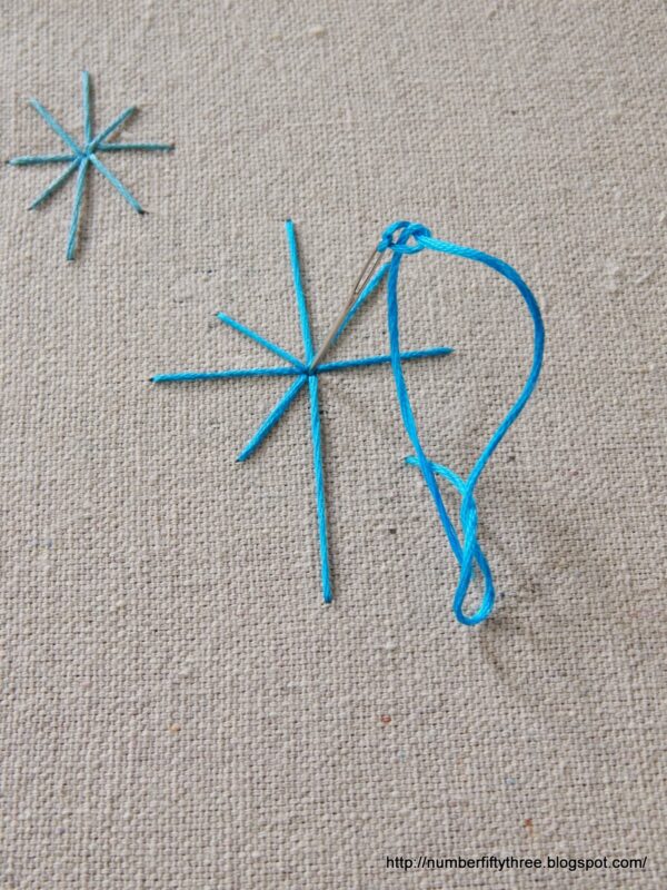 This easy DIY beginner embroidery project displays blue thread creating star shapes on beige fabric, perfect for adding a touch of charm.