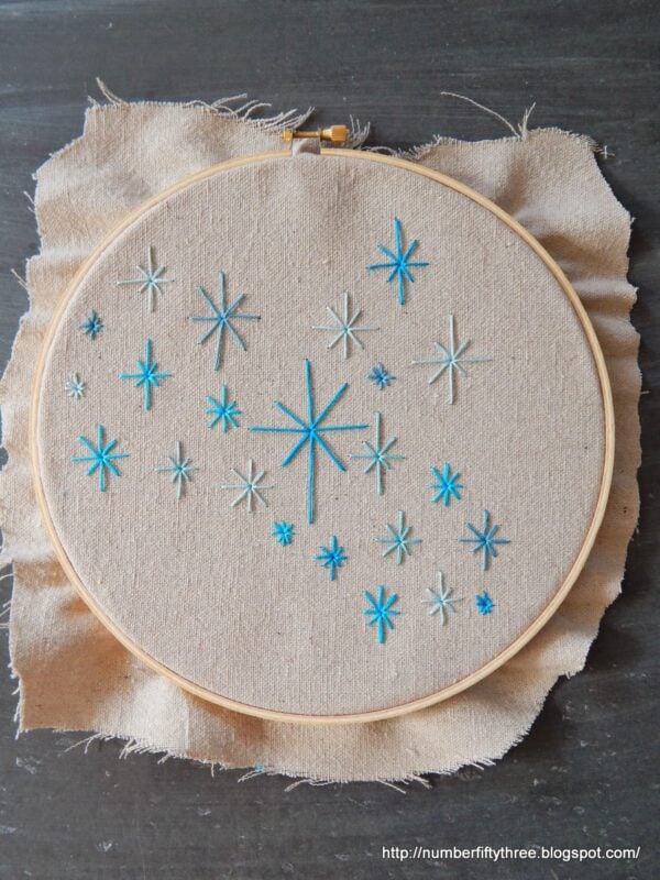 This easy DIY embroidery project is perfect for beginners, featuring a delightful hoop with blue star patterns stitched gracefully on beige fabric.