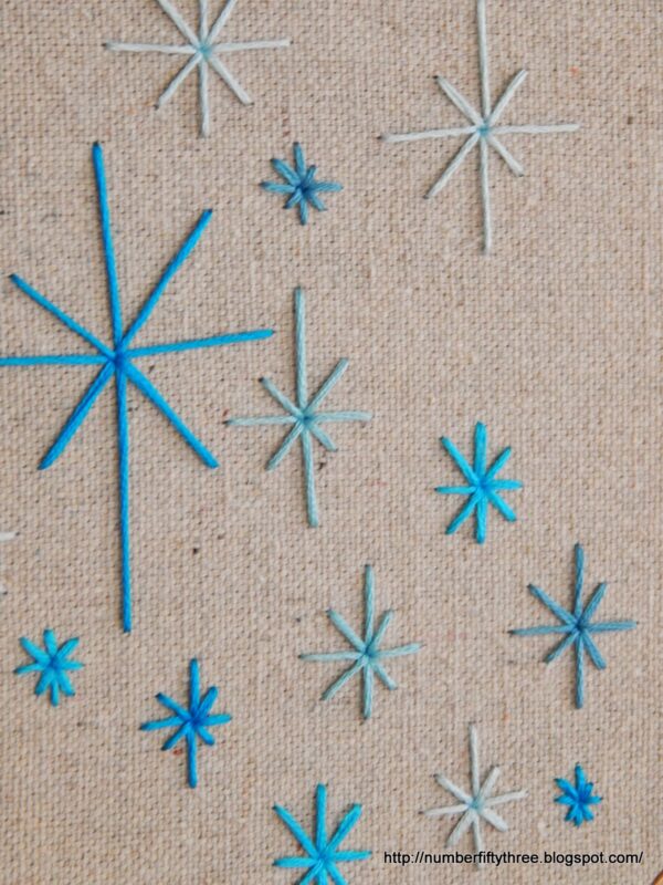 Blue and teal star patterns embroidered on a beige fabric background, perfect for an easy DIY beginner embroidery project.