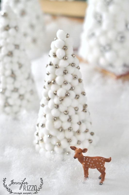 A small toy deer stands on fake snow before a cone-shaped Christmas tree adorned with white pom-poms and silver beads, capturing the festive spirit found in holiday book Creatively Christmas.