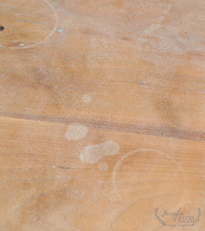 A wooden surface with visible water stains and rings from furniture.