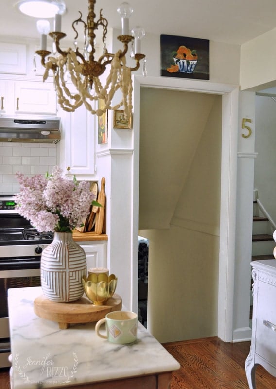 A kitchen with a chandelier and a marble island.