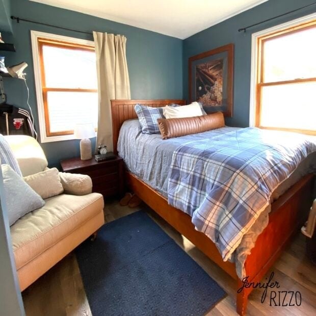 a older teen's bedroom with wood bed frame, blue carpet, beige chair and blue plaid bedding in a sports theme