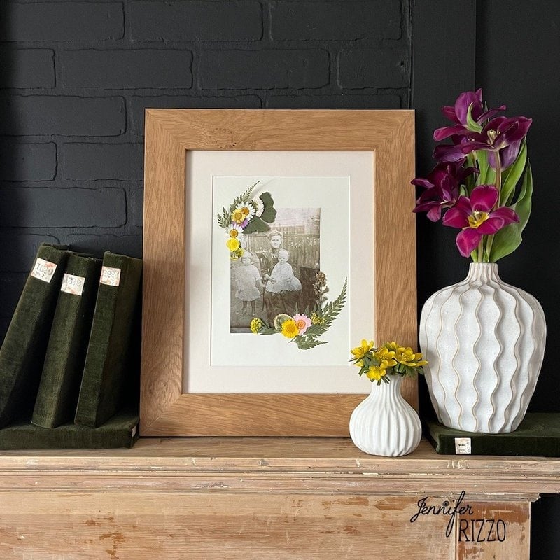 Framed dried flowers on a mantel with flowers