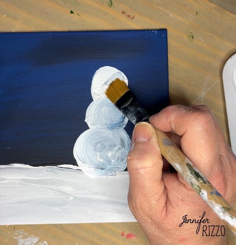 Person painting white circles on a dark blue canvas with a brush.