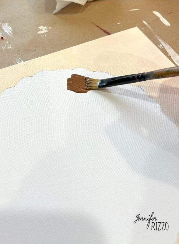 A paintbrush applies brown paint onto a white, cloud-shaped area on a canvas, creating Pumpkin Pie Wall Art, with the Jennifer Rizzo logo in the bottom right corner.