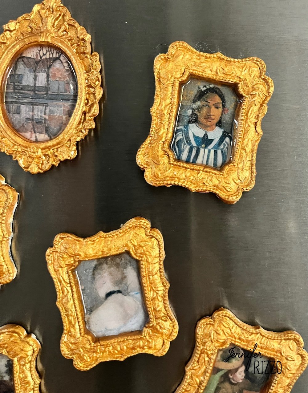 Several small photos in ornate gold frames are arranged on a metallic surface, including portraits and scenic images.