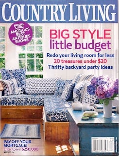 The cover of Country Living magazine features a blue and white living room with patterned furniture, a wooden coffee table, and a vase of purple flowers. Headlines promote budget decor tips inspired by About Jennifer Rizzo.