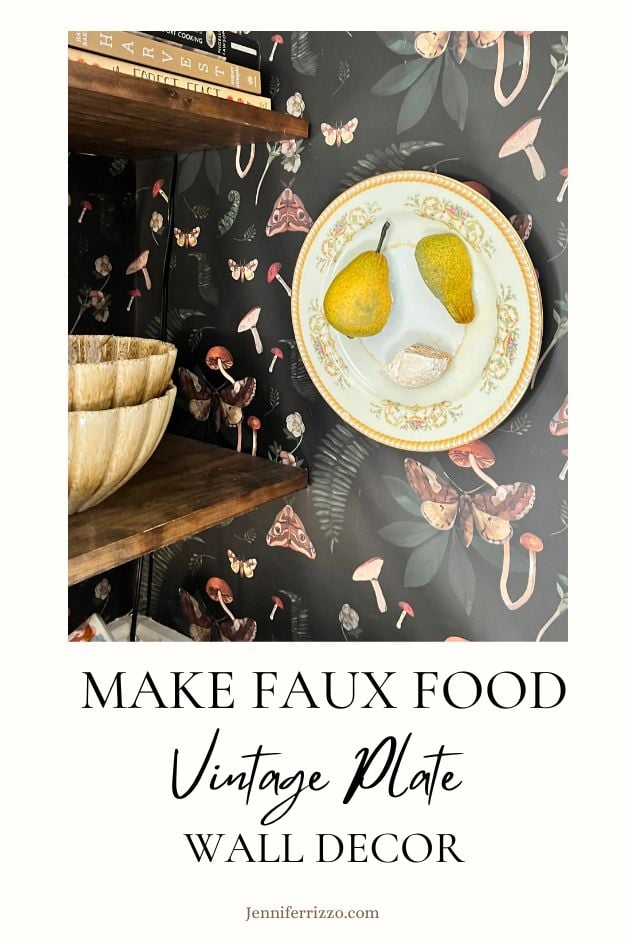 A decorative plate with faux pears and bread is mounted on a wall with botanical and butterfly wallpaper, next to wooden bowls on shelves. Text reads, "Make Faux Food Vintage Plate Wall Decor.
