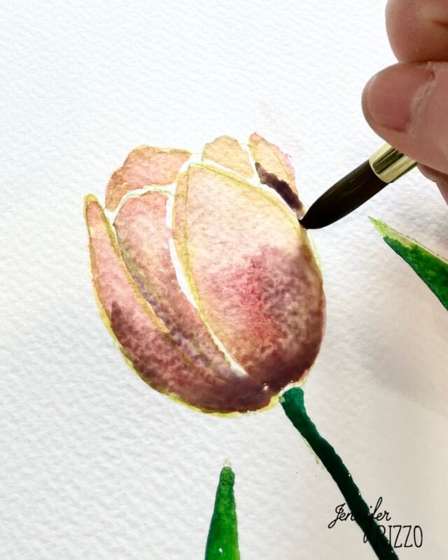 A hand uses a paintbrush to watercolor a pink and brown tulip on textured white paper. The artist’s signature, “Jennifer Rizzo,” is in the corner.