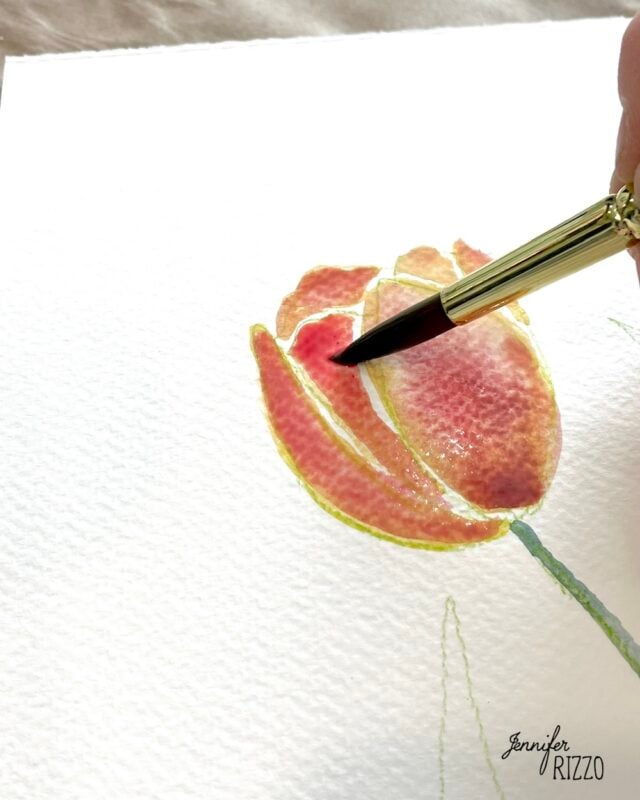 A close-up of a paintbrush applying red watercolor to a tulip flower on textured white paper, with "Jennifer Rizzo" signed in the corner.