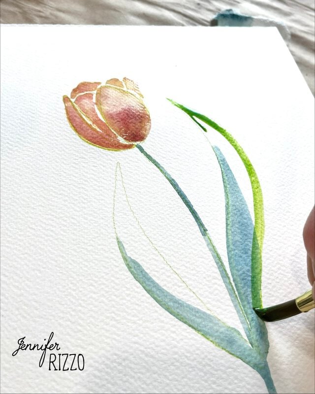 A hand uses a paintbrush to create a watercolor painting of a tulip with green leaves on white paper. "Jennifer Rizzo" is written in the lower left corner.