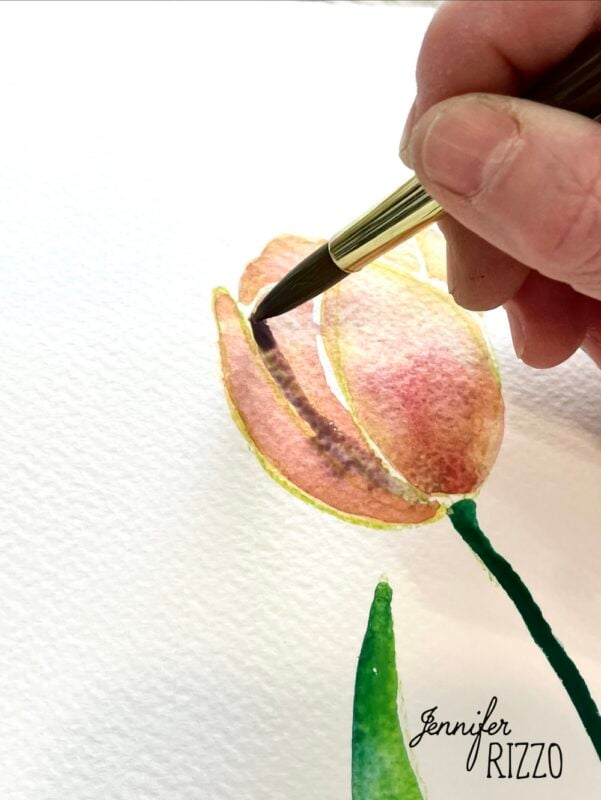 A hand uses a paintbrush to paint a pink and yellow tulip with green stem on textured white paper. The name "Jennifer Rizzo" is written in the corner.