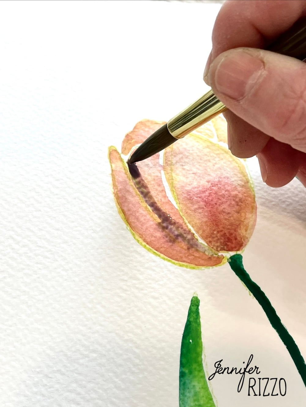 A hand uses a paintbrush to paint a pink and yellow tulip with green stem on textured white paper. The name "Jennifer Rizzo" is written in the corner.