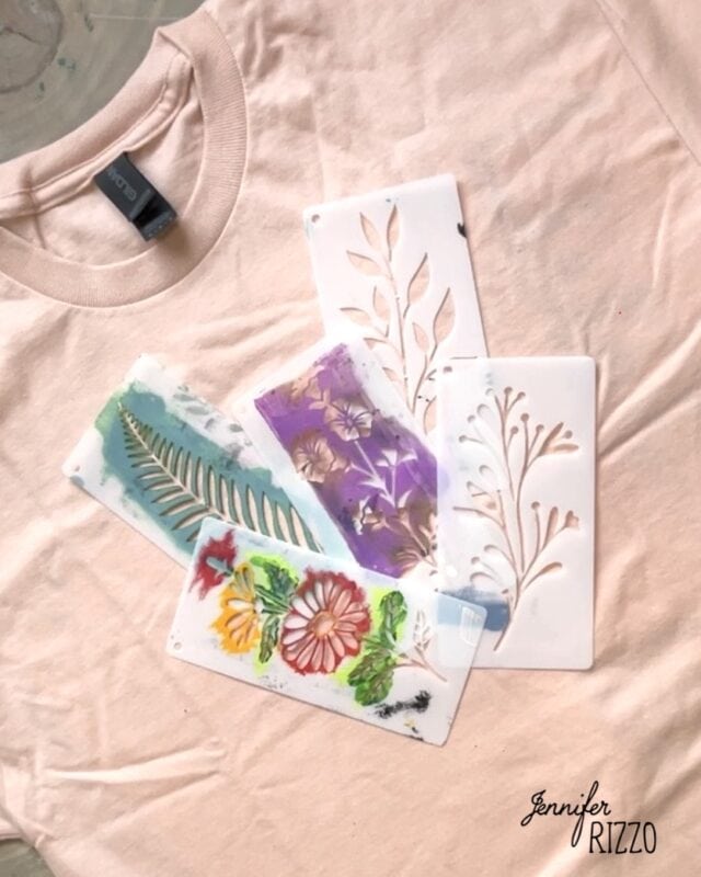 A light pink t-shirt with four Batik with Glue and Stencils featuring leaf and flower designs placed on top, some with paint residue. "Jennifer Rizzo" is written in the bottom right corner.