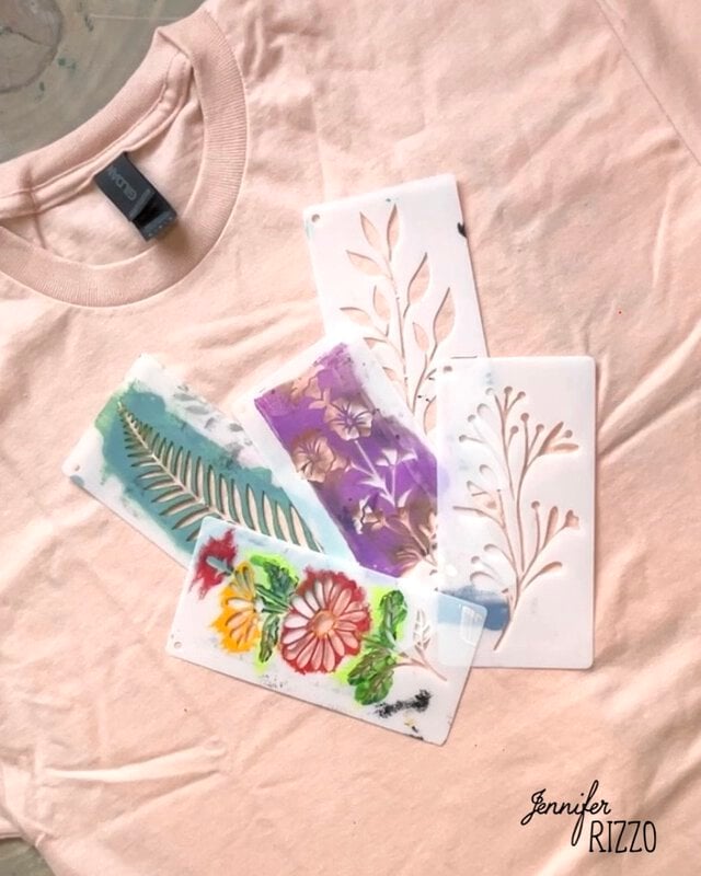 A light pink t-shirt with four Batik with Glue and Stencils featuring leaf and flower designs placed on top, some with paint residue. "Jennifer Rizzo" is written in the bottom right corner.