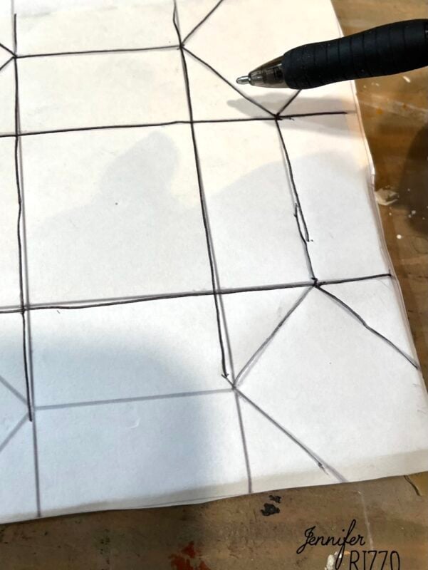 A pen drawing straight and diagonal lines on a sheet of white paper, creating a grid and triangular shapes—reminiscent of Easy Kinusaiga Art patterns.