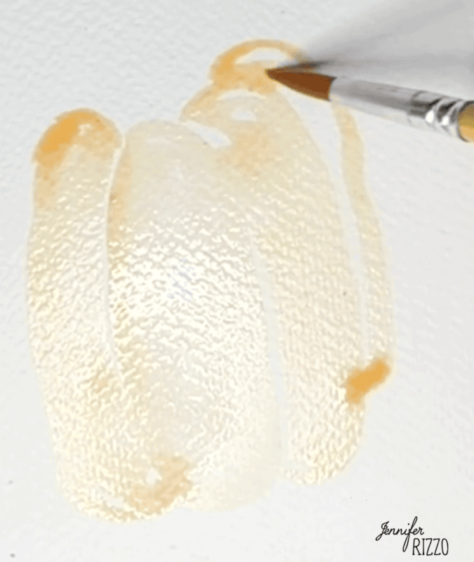 A paintbrush applies light orange watercolor paint in loose strokes on textured white paper.