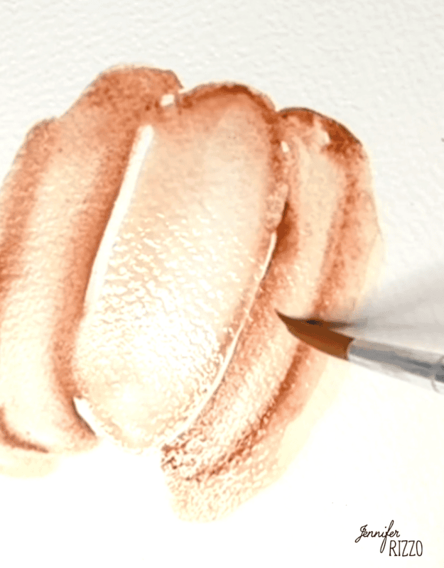 A paintbrush applies light brown watercolor strokes onto textured white paper, creating overlapping shapes.