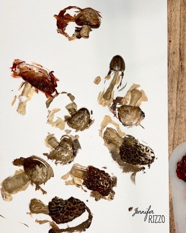 A white canvas with multiple brown and black mushroom prints, featuring varied textures and shapes, on a wooden surface. The name “Jennifer Rizzo” is printed in the corner.