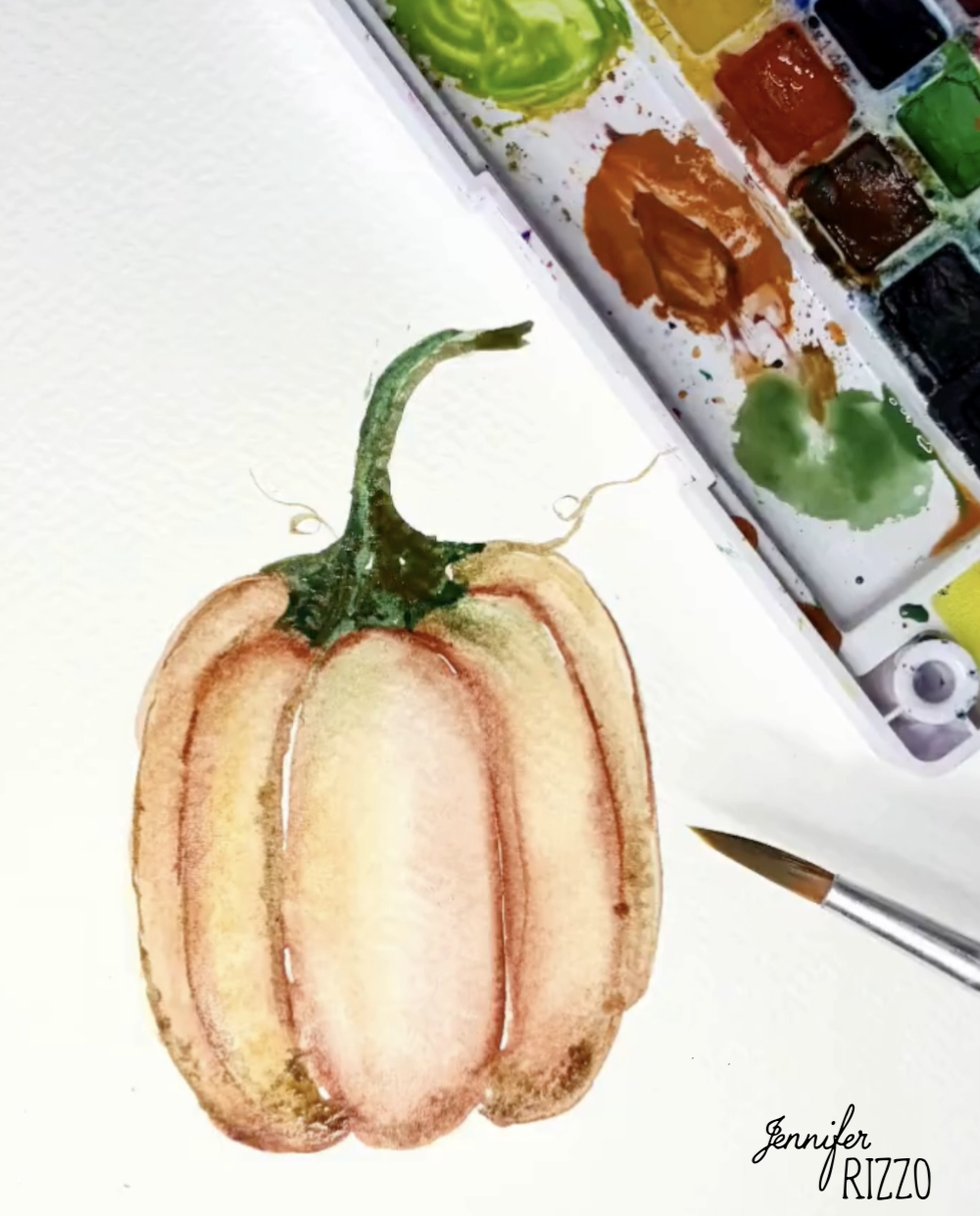 Watercolor painting of a pumpkin next to a paintbrush and a watercolor palette with various colors.