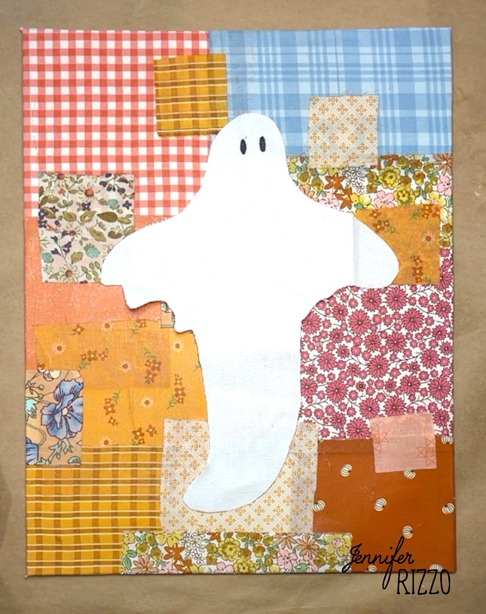 A white ghost shape is centered on a background of variously patterned and colored fabric squares.