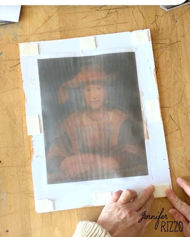 Hands hold a translucent paper over a painting of a person in a hat, taped to a white board on a wooden table. The name “Jennifer Rizzo” appears in the lower right corner.